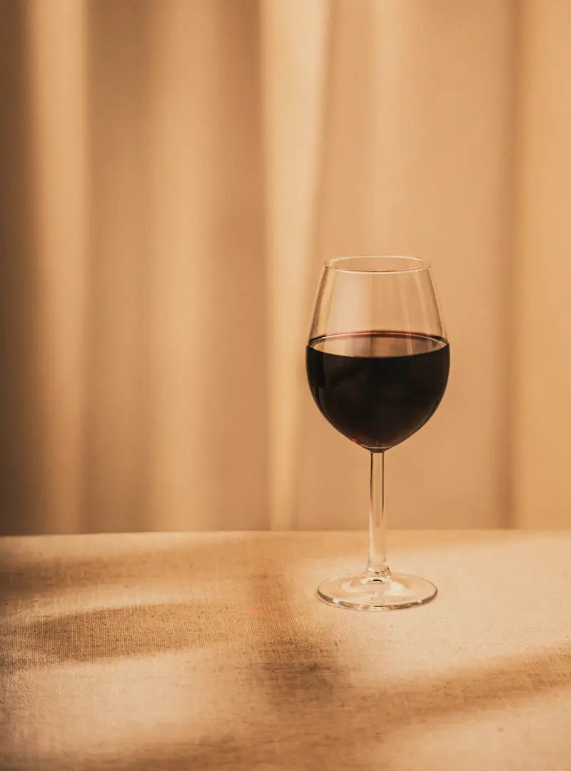 A single glass of red wine on a linen-covered table