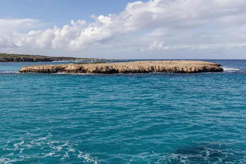 A low rocky islet in the clear water of the Blue Lagoon, Akamas