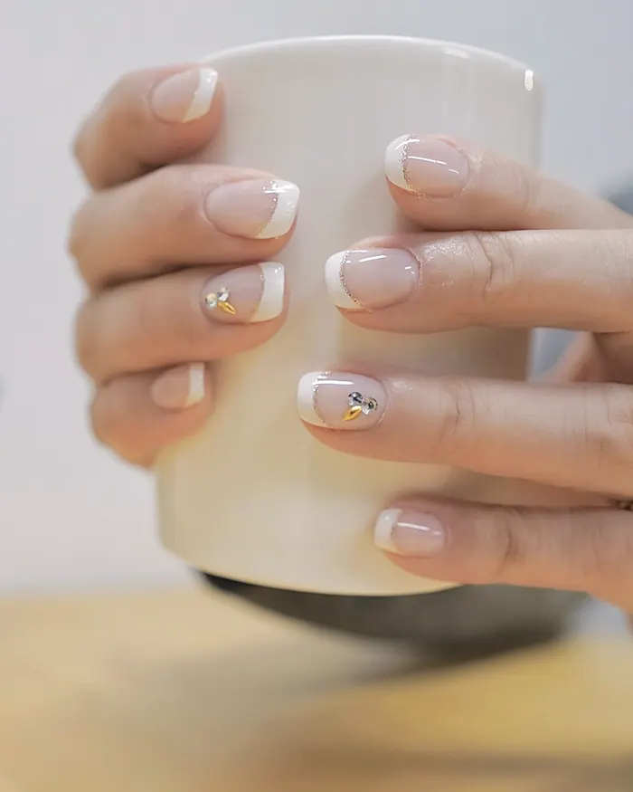 Hands with a fine French tip holding a white coffee mug
