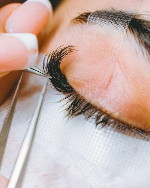 A lash artist placing a single eyelash extension with fine tweezers