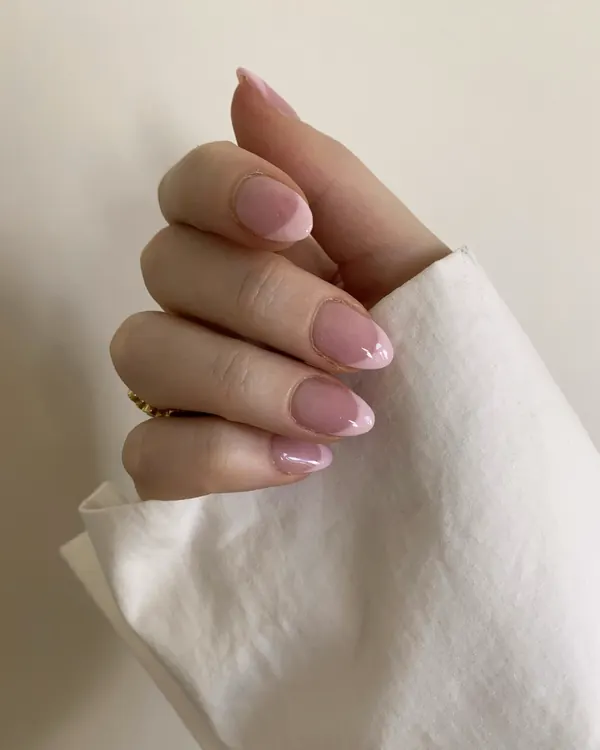 A hand with soft pink almond nails holding a linen napkin