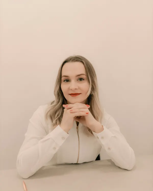 Portrait of Elena sitting at a table with her hands folded