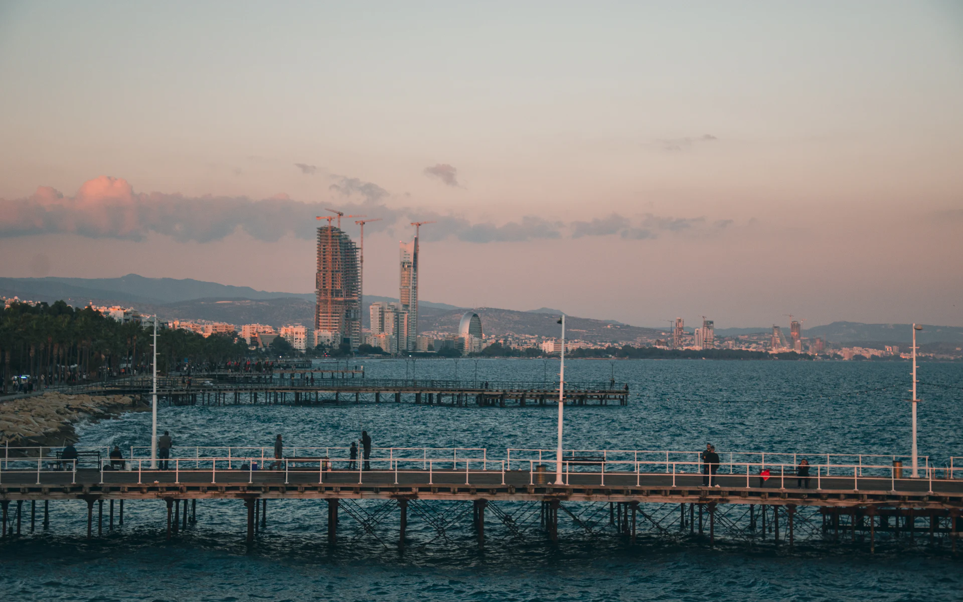 Limassol seafront promenade and pier at dusk, with the towers of the city behind