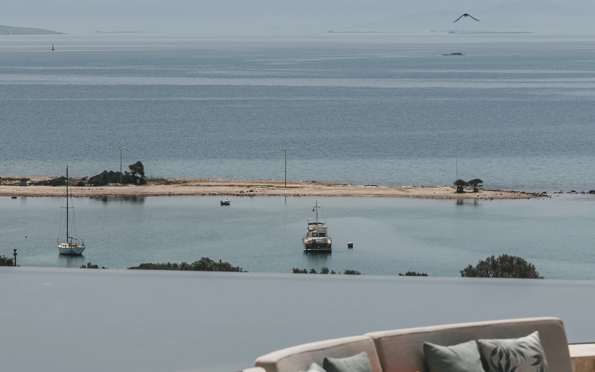 Curved outdoor sofa beside an infinity pool above a calm sea