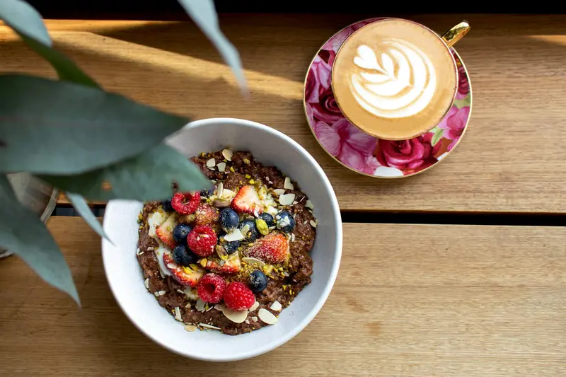 Granola bowl with berries next to a latte
