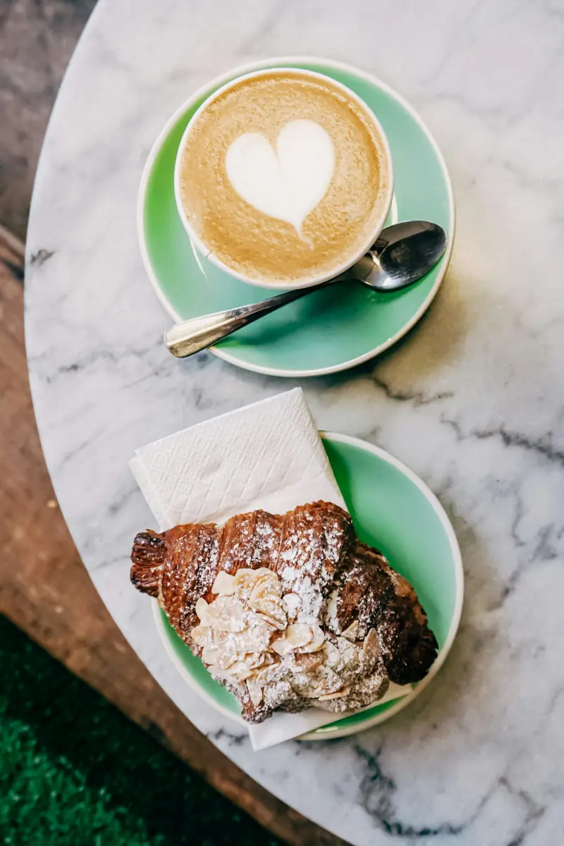 Latte and a slice of cake on green plates